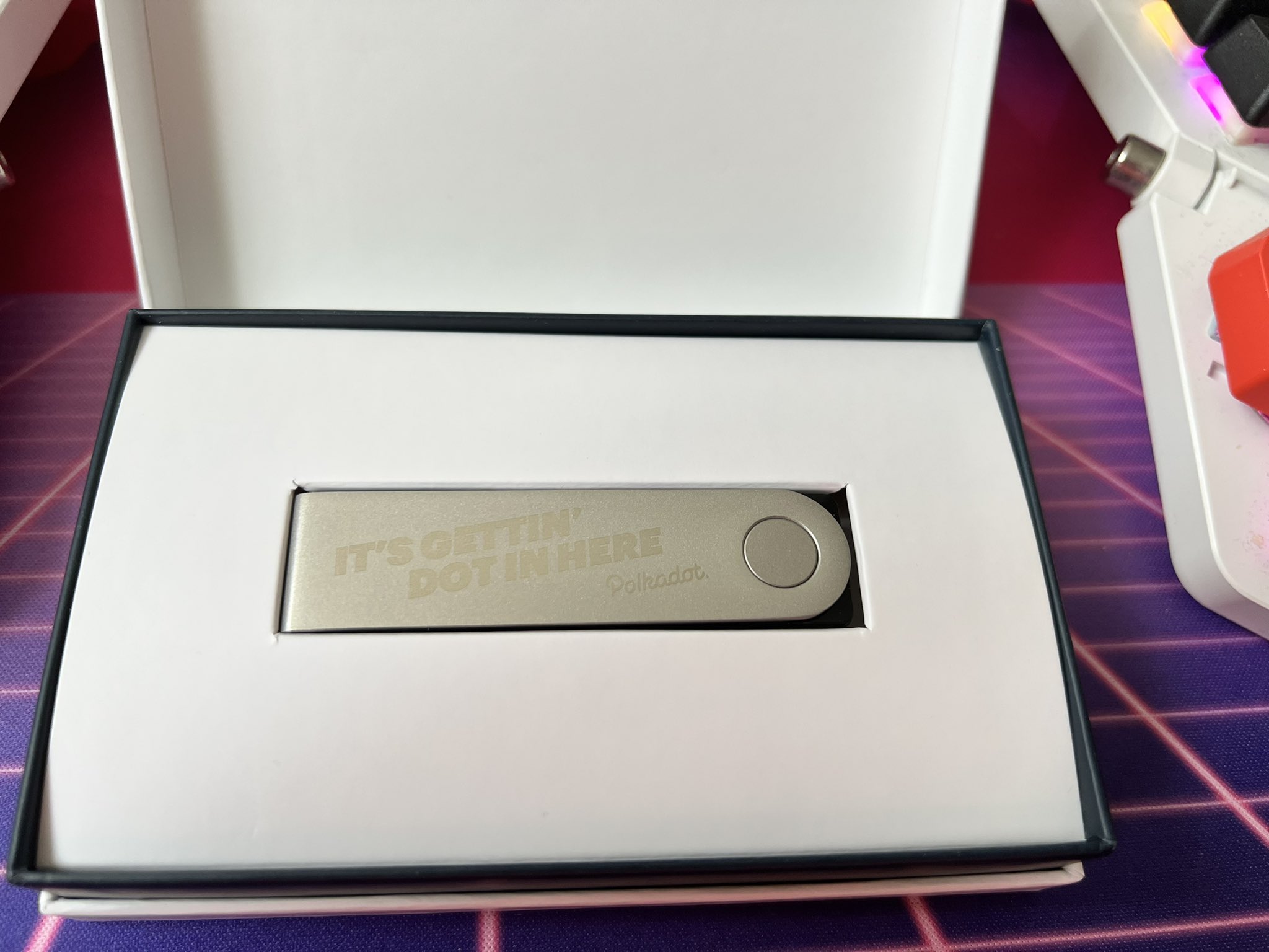 The device, looking vaguely like a USB stick with the engraving "it's getting dot in here" followed by the logo for Polkadot, some kind of blockchain thing