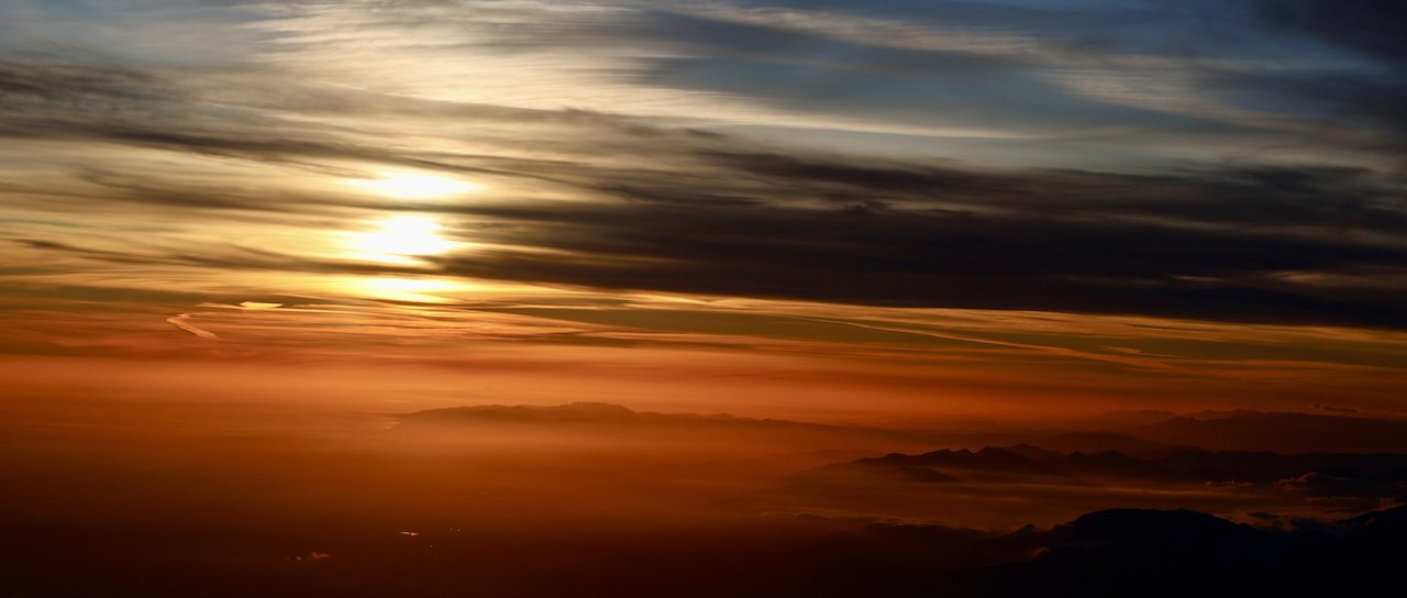 An image of Aerial view of a sunset over Los Angeles, California, USA, the sky is cloudy and there are layers of colored light