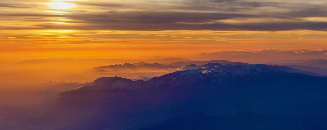 An image of A picture of the Los Angeles foothills near the airport at sunset. The sky is bathed in gold with the mountains a calming purple.